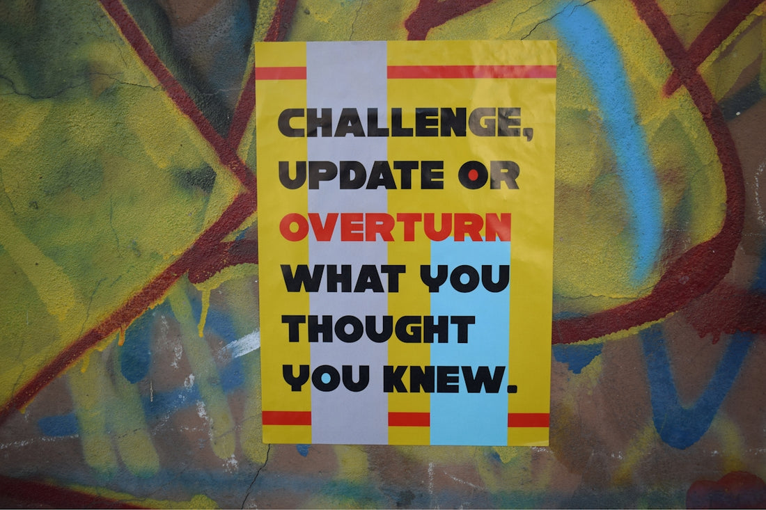 a yellow sign that says challenge update or overturn what you thought you knew